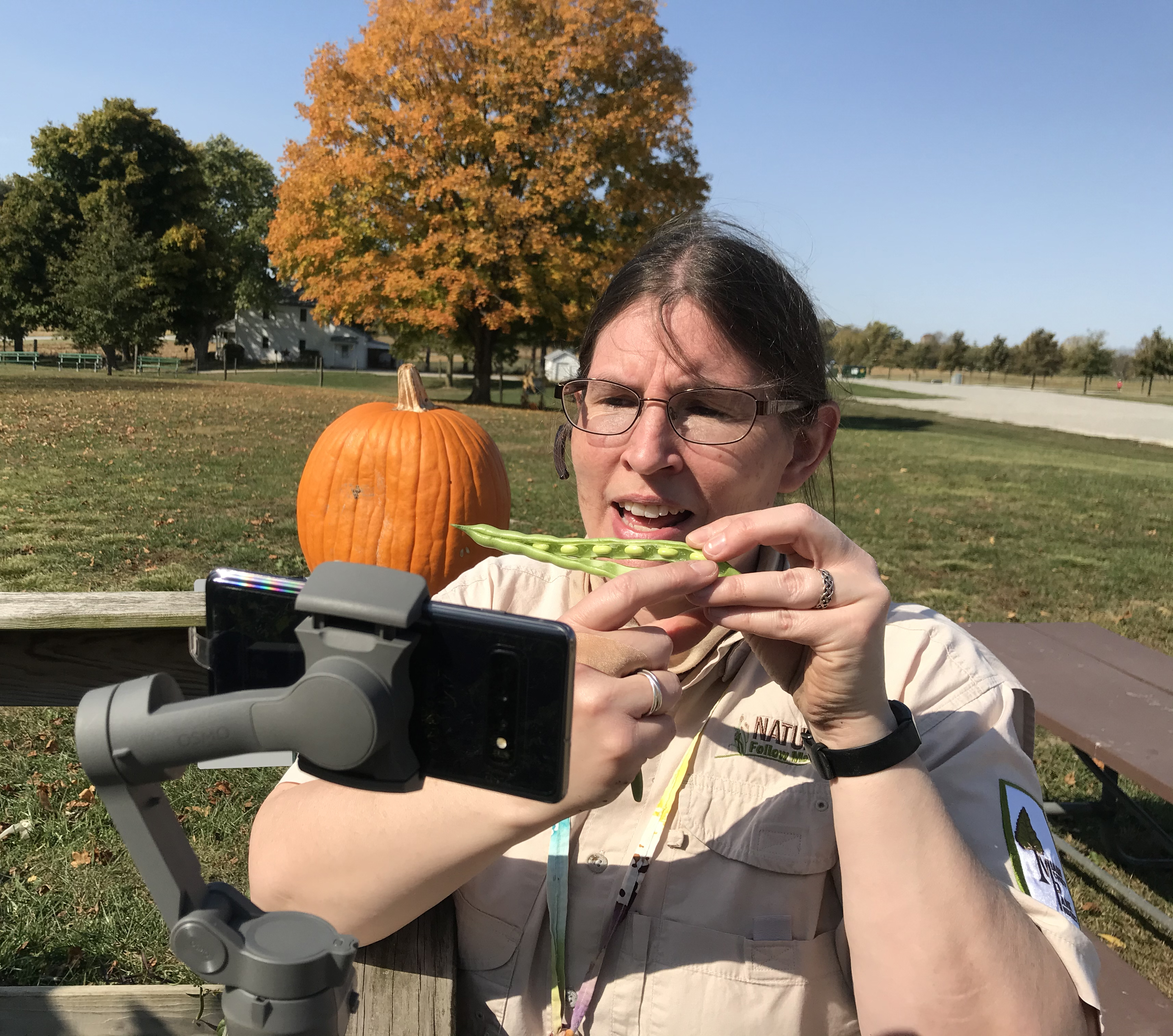 Naturalist showing a pumpkin in front of a camera.