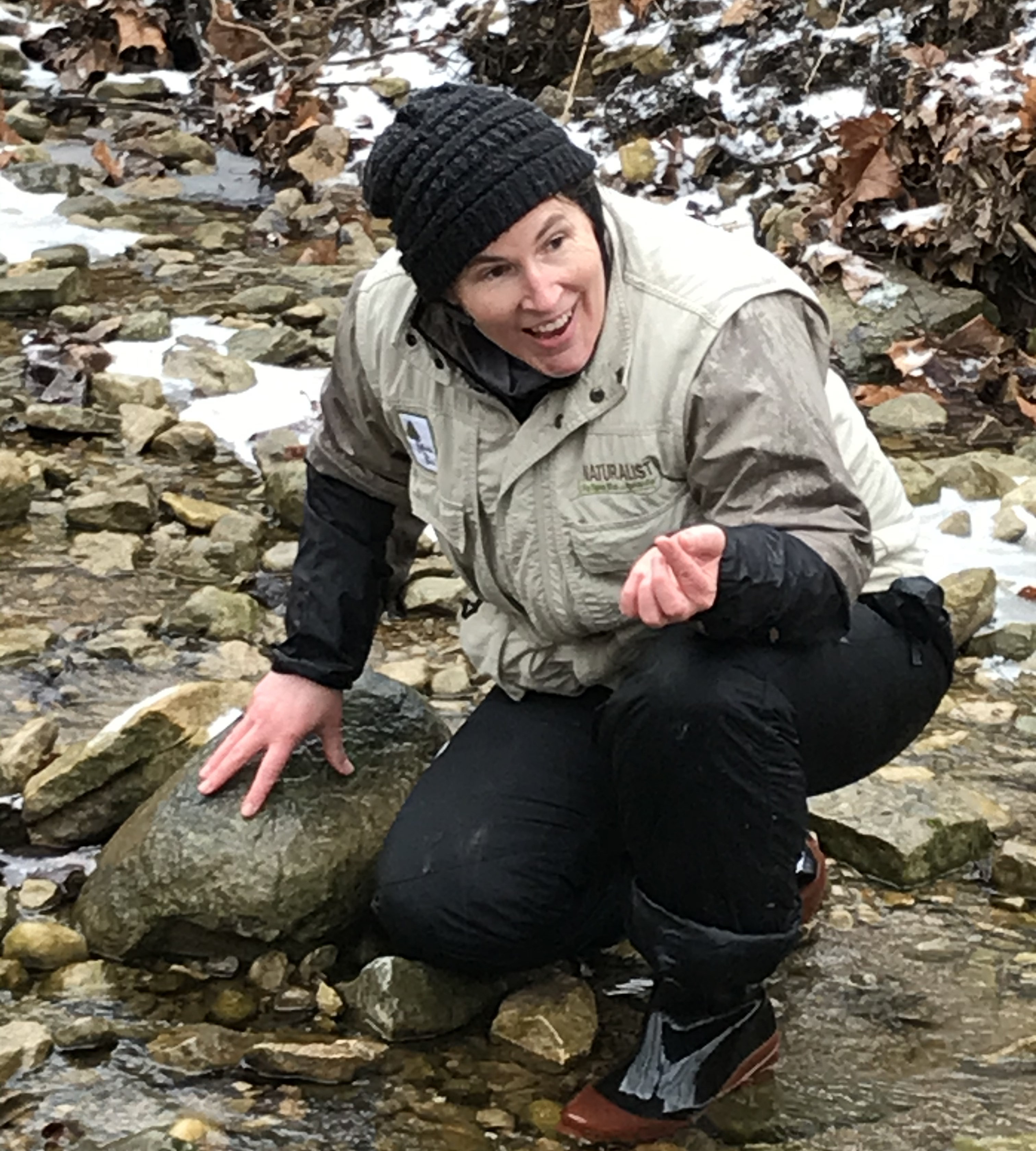 Naturalist kneeling by a stream