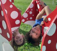 Boy and girl playing large red play mushrooms