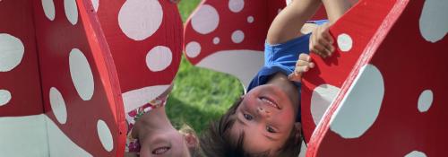Boy and girl playing large red play mushrooms